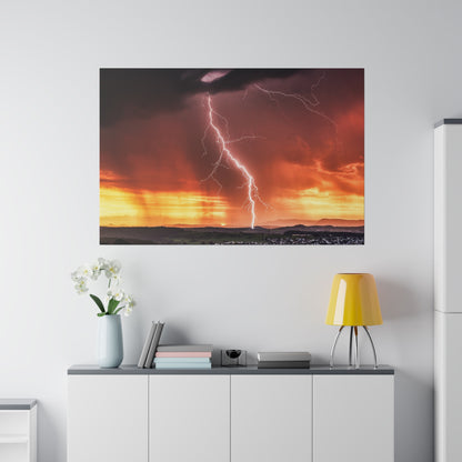 Large landscape photograph of a lightning bolt striking the ground during a fiery orange sunset, mounted on a white wall above a sideboard.