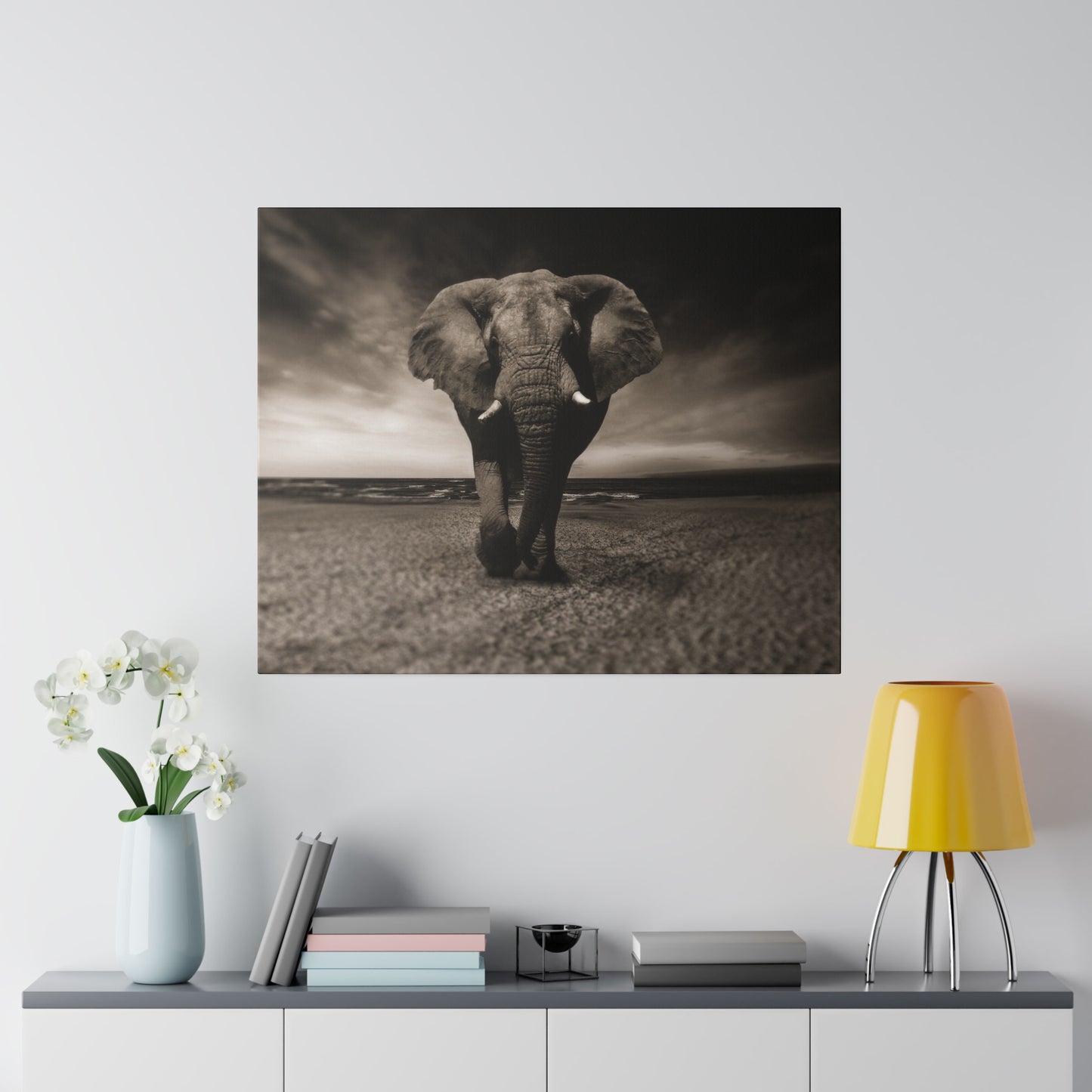 An elephant walking along the beachfront, its large ears flaring and tusks prominently displayed, against the serene ocean backdrop.