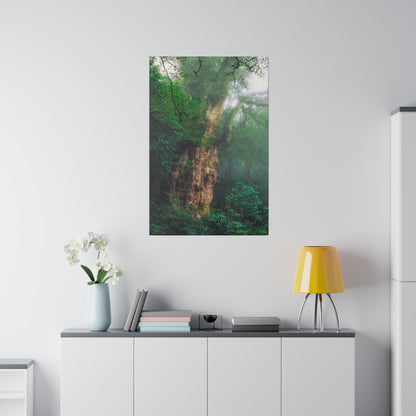 Vertical wall poster of a lush green forest tree above a white cabinet with a yellow table lamp and a vase of white orchids.