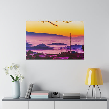 Framed wall art depicting a sunrise over purple misty hills with orange sky and silhouettes of buildings.