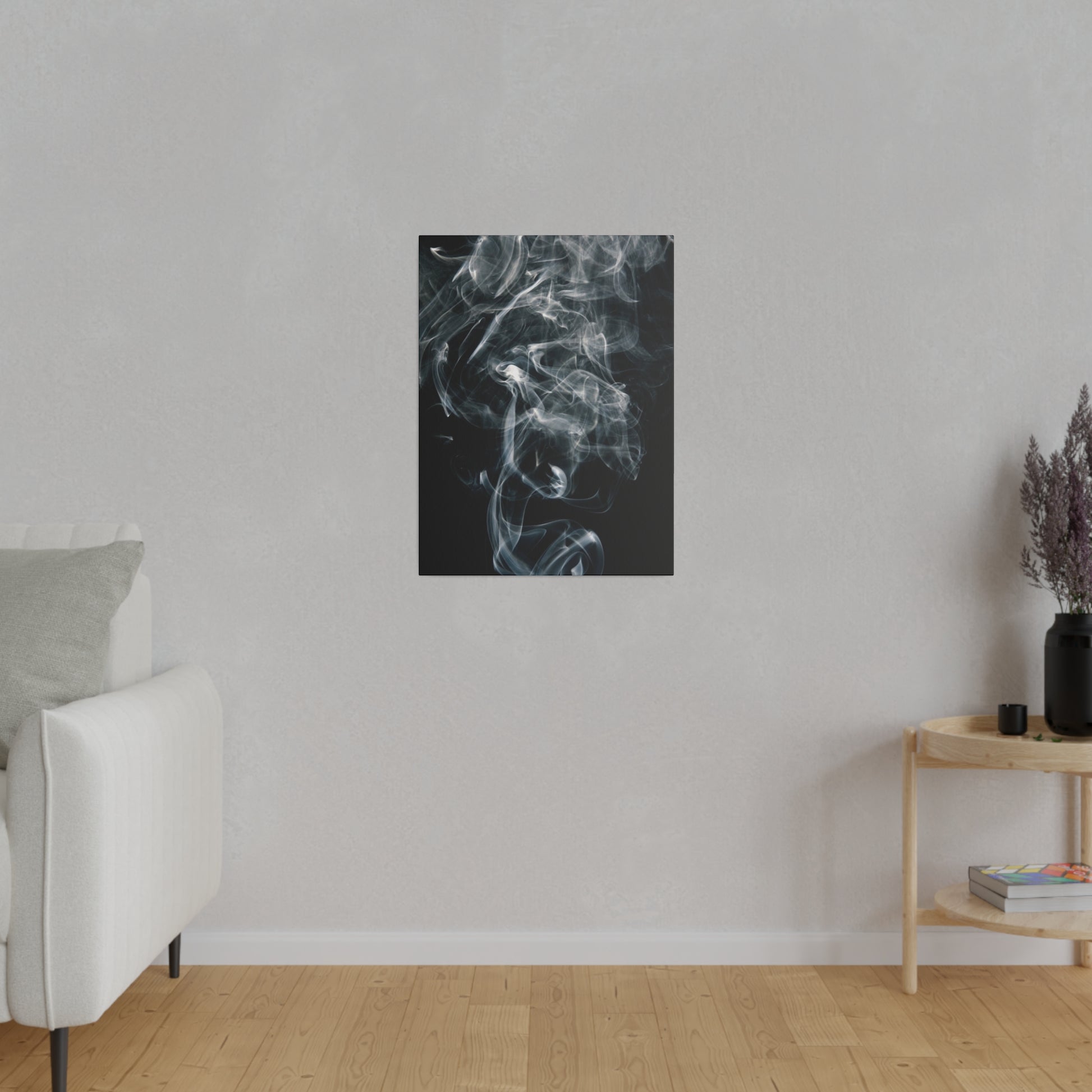 Vertical black artwork with white smoke hangs on a light gray wall above a white sofa in a minimalist living room.