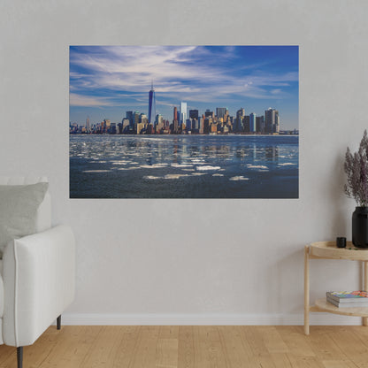 New York City skyline across a partially frozen harbor with scattered ice floes and a blue sky.