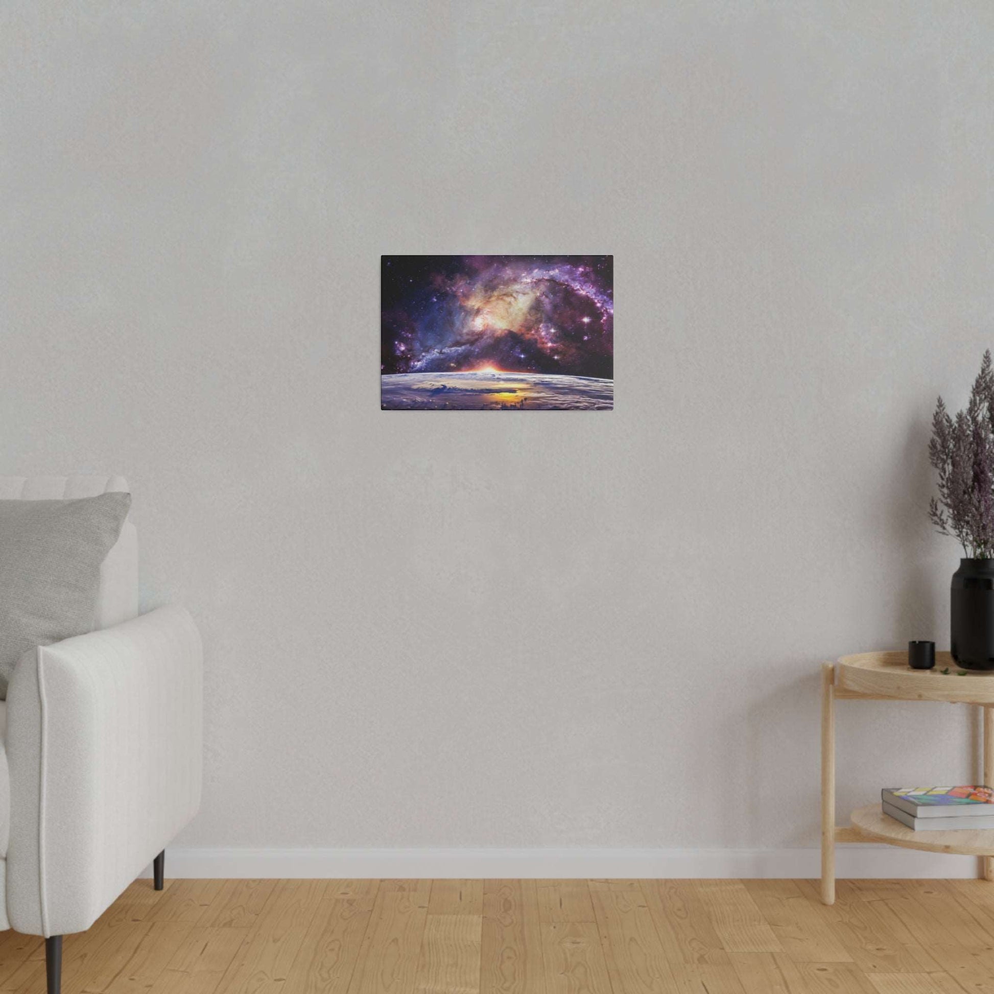 Small rectangular canvas print of a starry galaxy above a planetary horizon, mounted on a light gray wall in a minimalist living room.