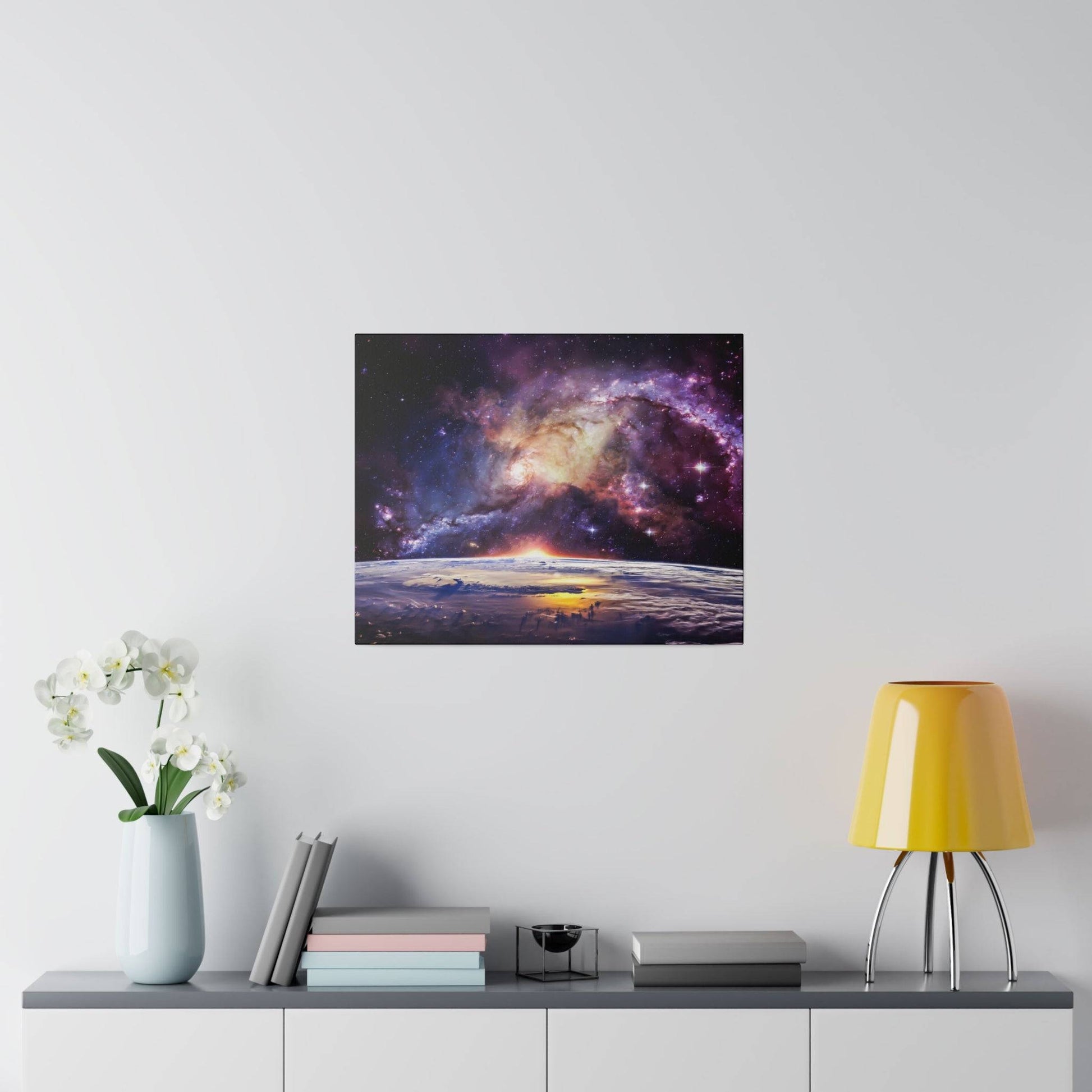 Square wall art showing a colorful galaxy over a sunrise horizon, mounted above a gray sideboard in a modern room.