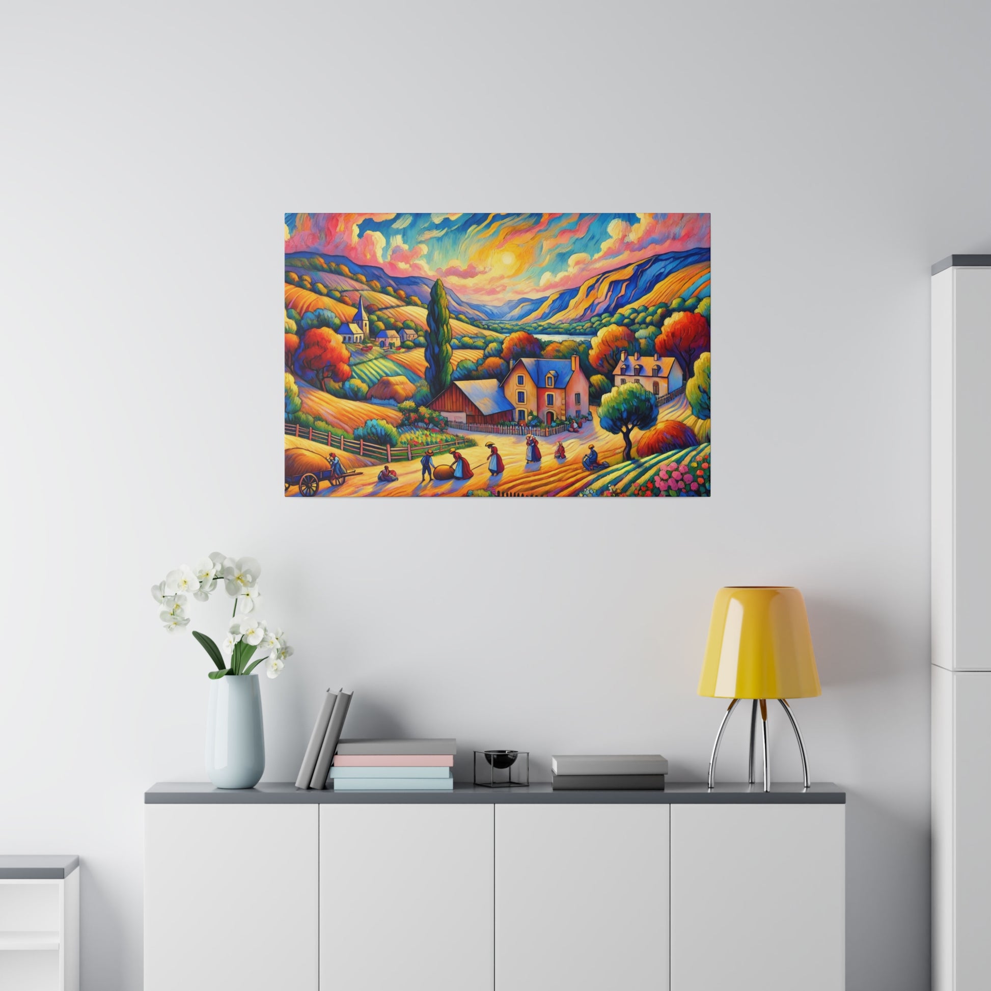 Colorful landscape painting with hills, houses, and trees hangs above a white cabinet in a bright, minimalist room.