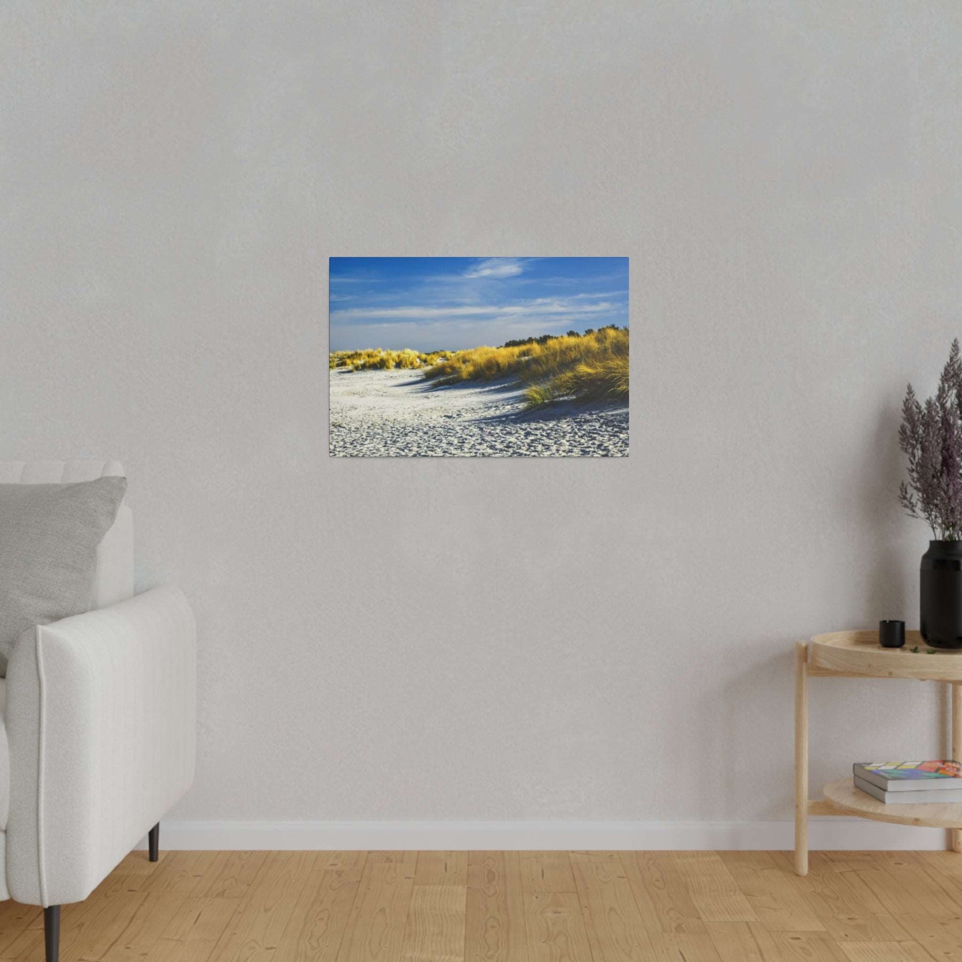 Small horizontal photograph of a beach with white sand dunes and golden grasses under a blue sky.