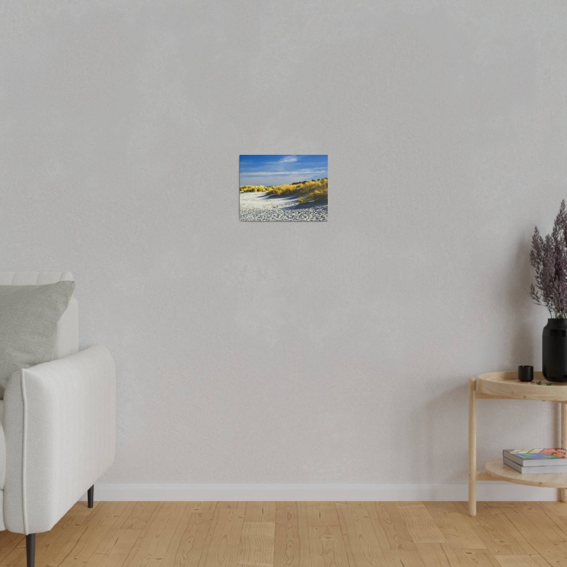 Small square canvas on a gray wall showing a sandy beach with golden grasses and blue sky.
