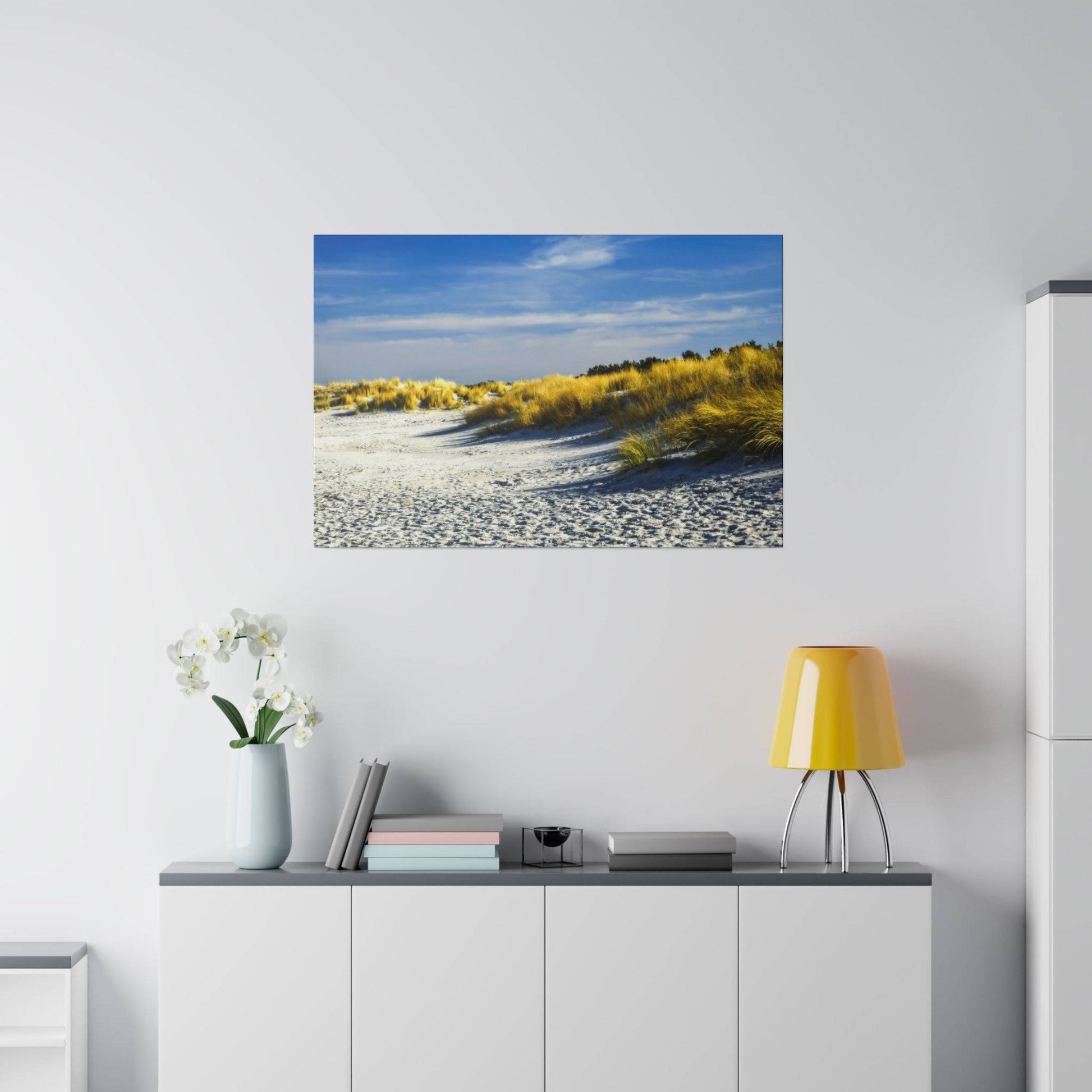 Framed beach landscape photograph showing white sand dunes with yellow grasses under a blue sky.