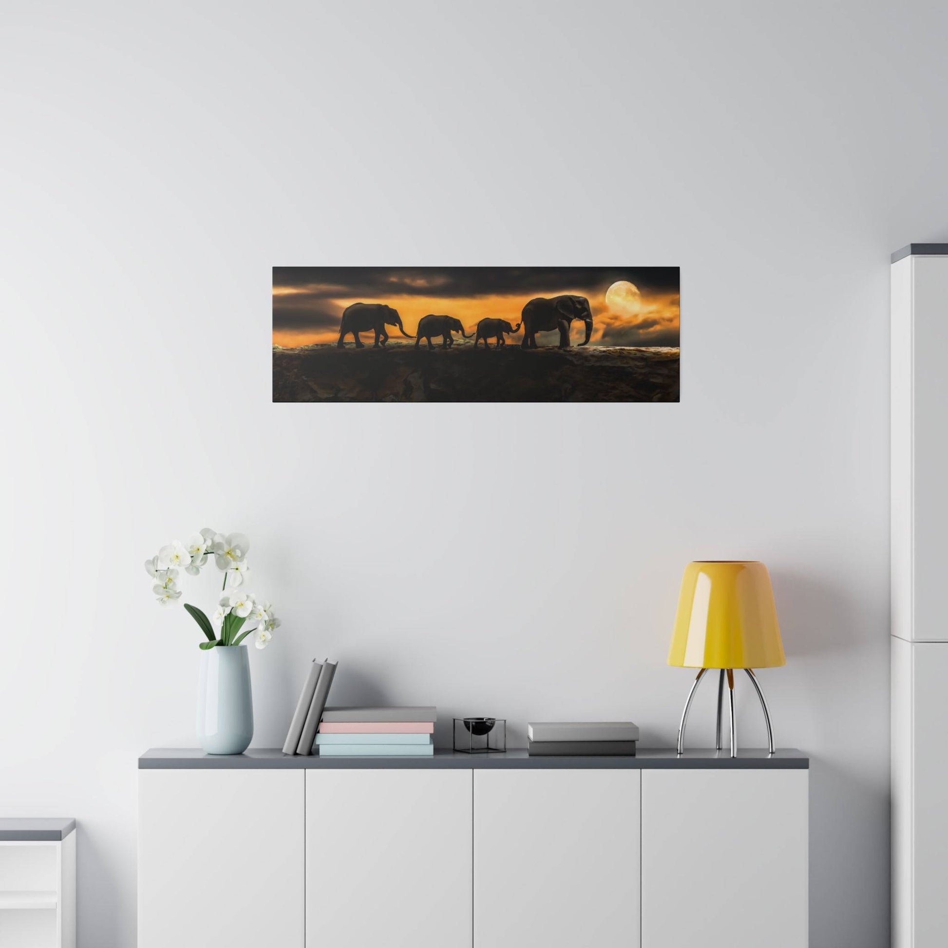 Horizontal wall art depicting silhouettes of elephants walking on a ridge at sunset.