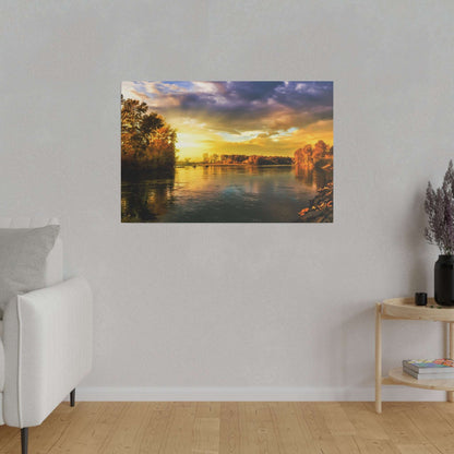 Wide river at sunset with orange and gold sky, trees along both banks, calm water reflecting the colors.