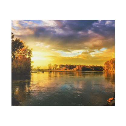 A wide river reflects a golden sunset with orange-tinted trees along the banks and a partly cloudy sky.