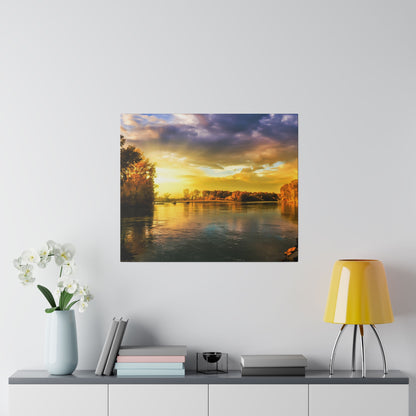 Square wall art showing a sunset over a calm river with golden light and trees along the banks.