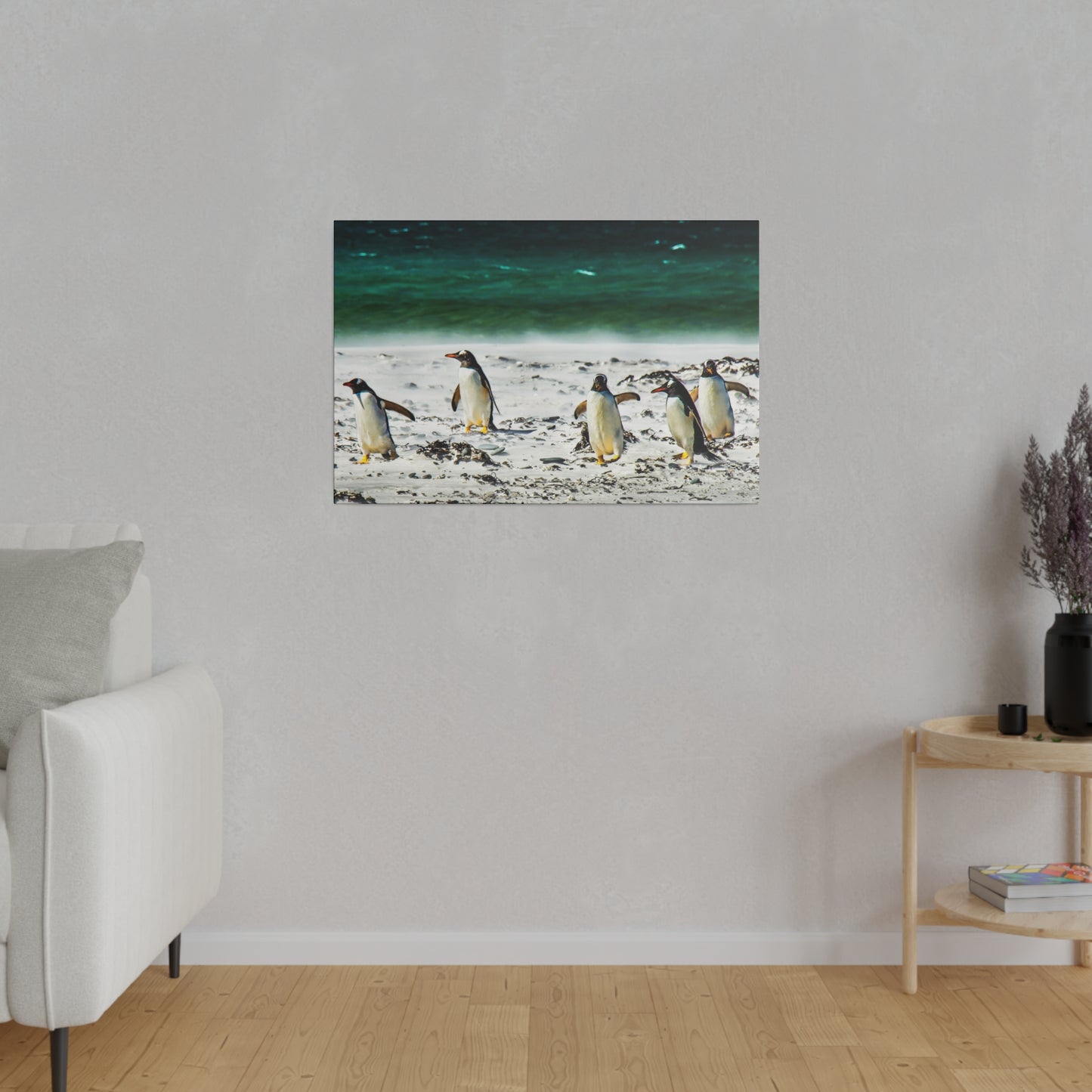 A group of penguins on a beach near the ocean. The penguins are walking along the sand, with the sea waves creating a peaceful atmosphere.