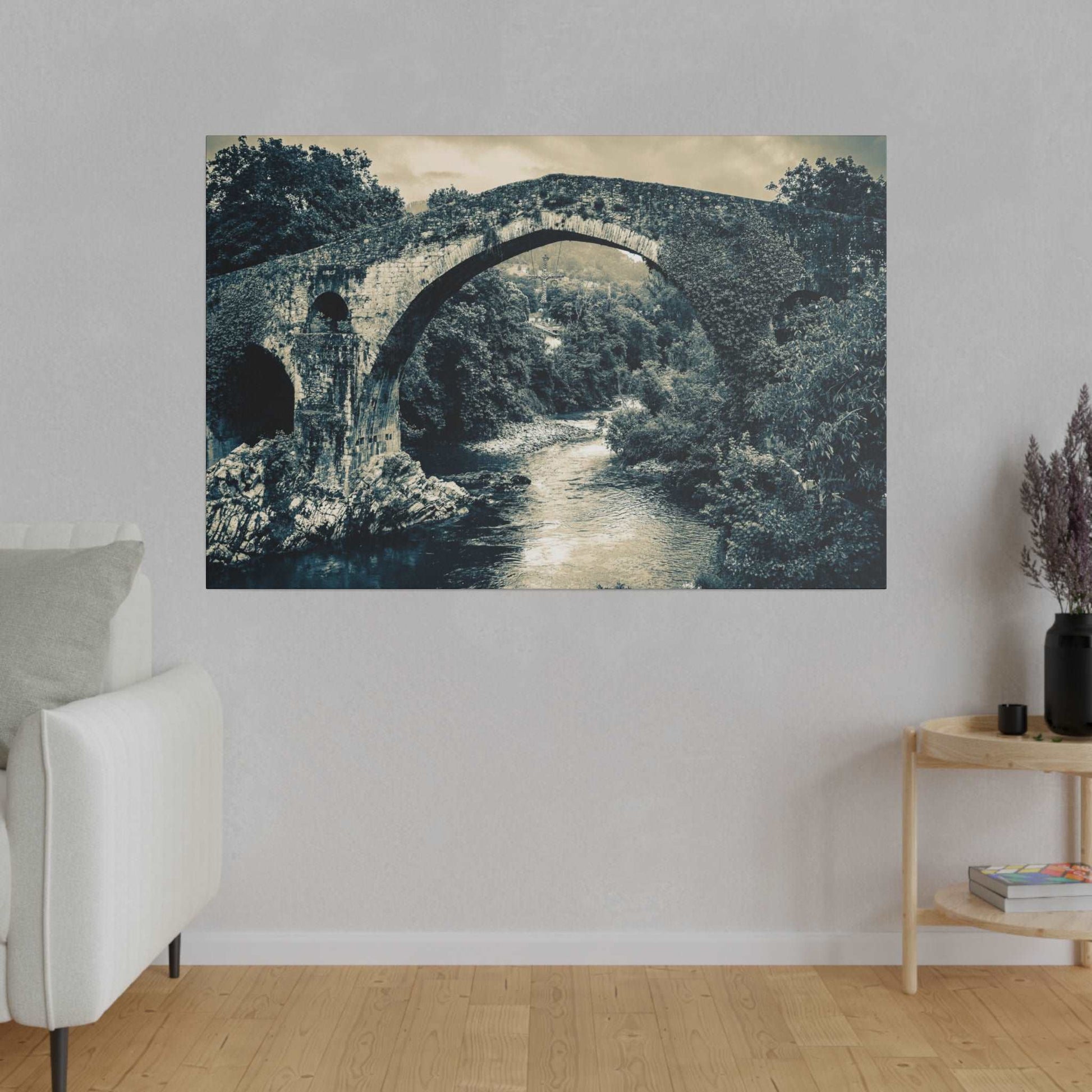 Black-and-white canvas print of an ancient stone arch bridge over a flowing river, surrounded by trees.