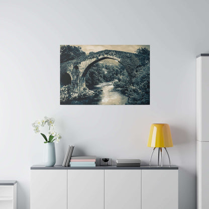 Monochrome canvas print of a historic stone arch bridge over a river, mounted on a light wall above a cabinet.
