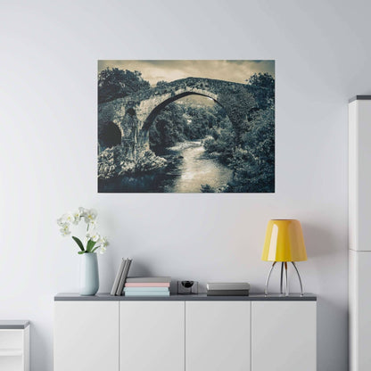 Canvas print of a historic stone arch bridge over a river, hung on a light wall above a sideboard.
