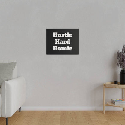 Light gray living room wall with a centered black square sign reading 'Hustle Hard Homie' above a light sofa and wooden side table.