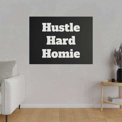 Black wall poster reading 'Hustle Hard Homie' in bold white letters hangs above a small wooden side table in a light gray living room.