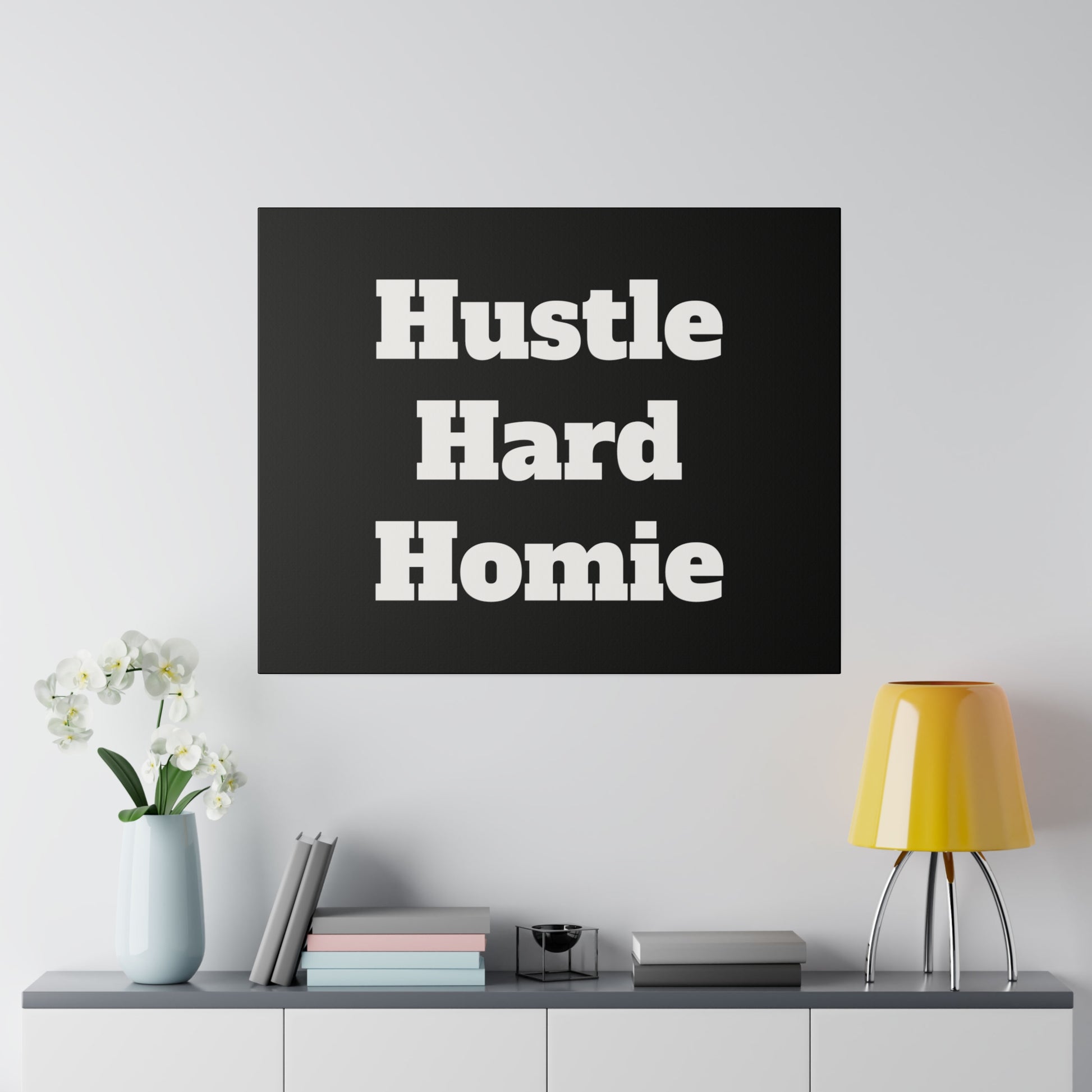Black square wall art displays bold white text: “Hustle Hard Homie” stacked on three lines.