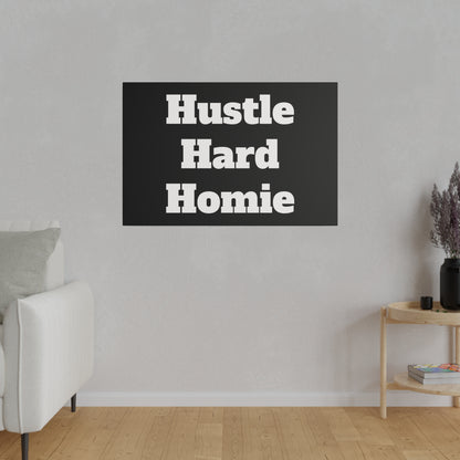 Living room wall with a black poster reading "Hustle Hard Homie" above a white sofa and a wooden side table.