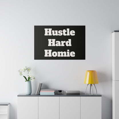 Black rectangular poster with bold white text "Hustle Hard Homie" hung above a white cabinet with a yellow lamp.