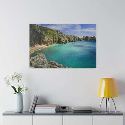 Framed coastal landscape featuring turquoise cove, rocky cliffs, and sandy beach under blue sky.