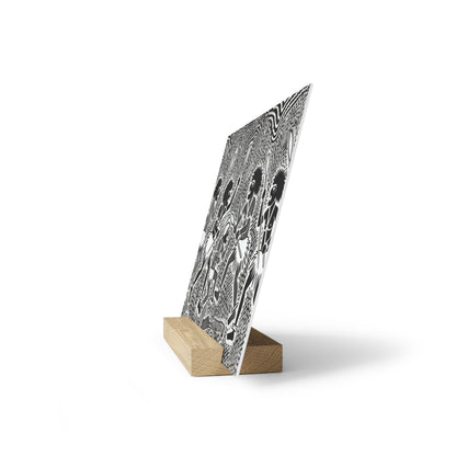 Black-and-white patterned poster on a small wooden stand, tilted against a white background.