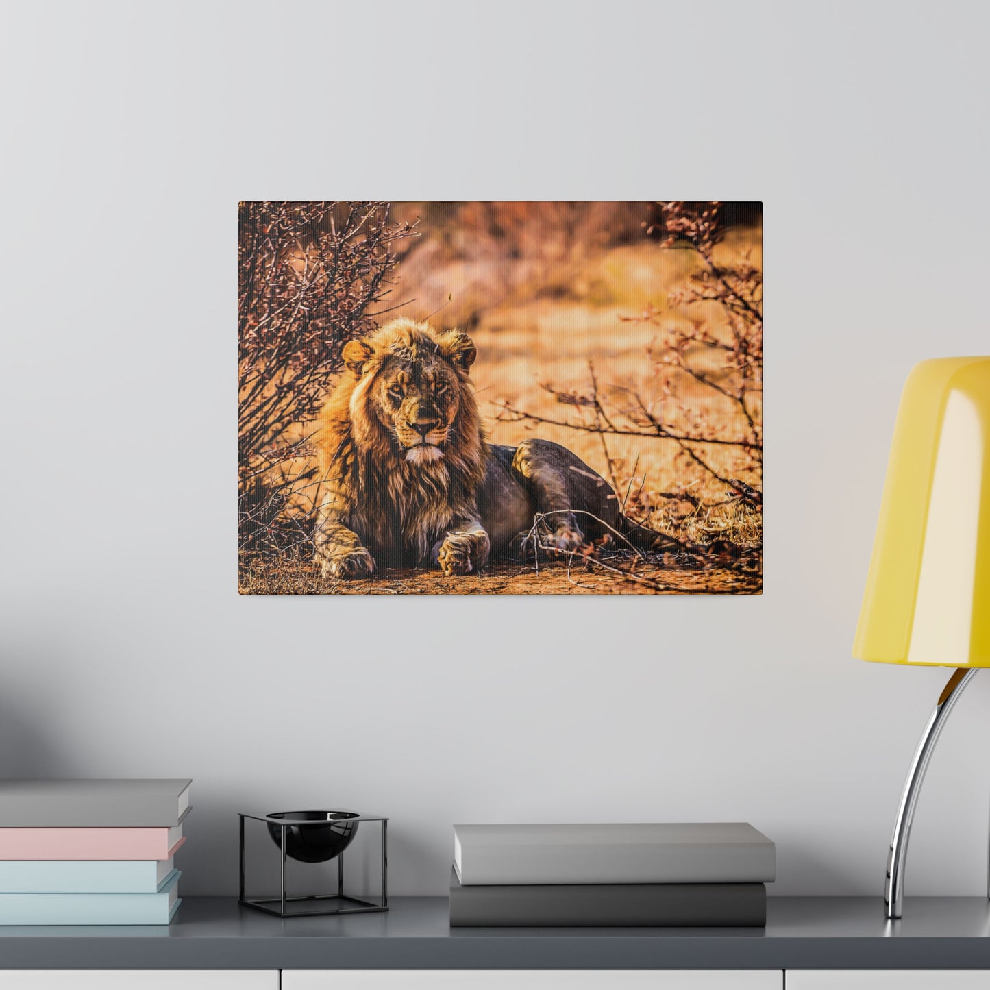 A lion resting among dry bushes in the savannah, with warm sunlight creating a serene atmosphere. The lion's regal mane and strong features are striking.