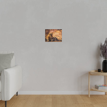 Small framed painting of a reclining lion in warm brown tones hanging on a light gray wall above a wooden floor.