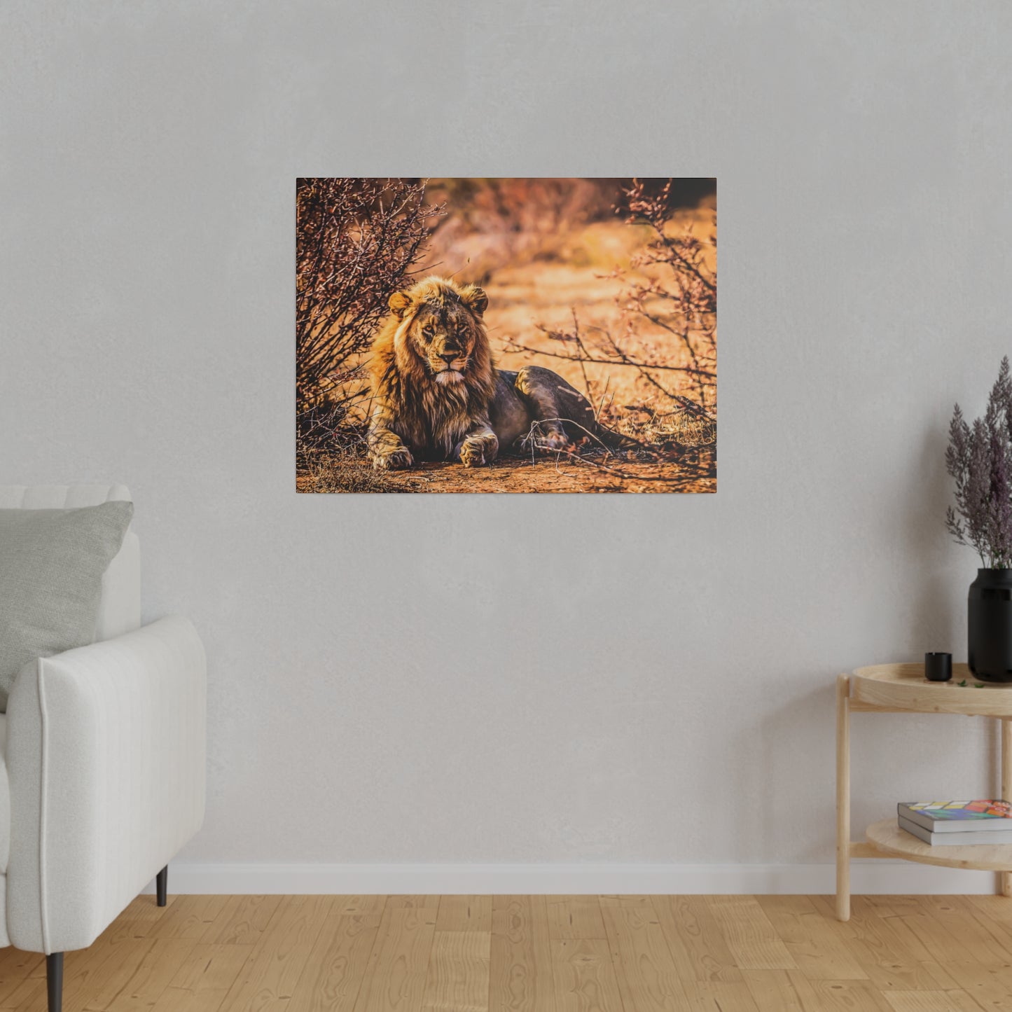 A lion relaxing in the savannah, surrounded by dry bushes and bathed in warm sunlight. The lion's majestic mane and calm demeanor are striking.