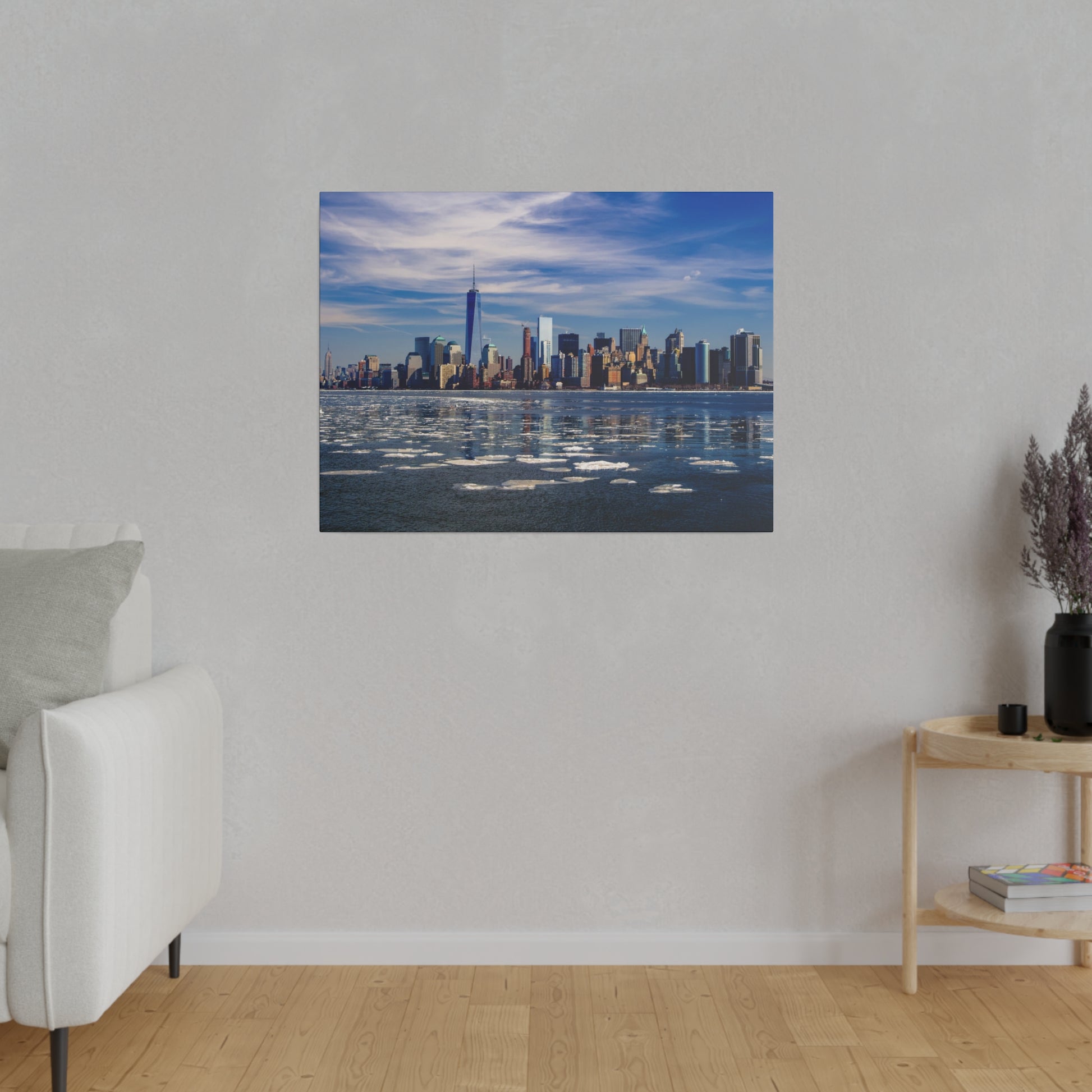 A clear view of the Lower Manhattan skyline with prominent skyscrapers standing tall against a blue sky, reflecting in the river.