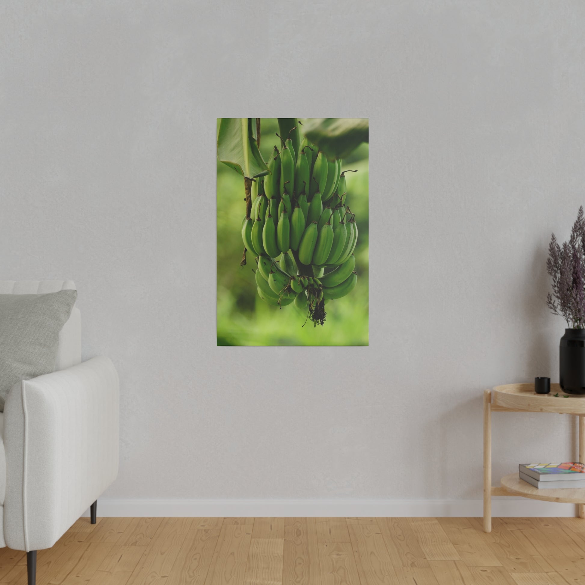 Vertical wall art depicting a green banana bunch hanging from a stem against a blurred green background.
