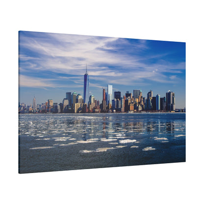 New York City skyline along a partly frozen harbor under a bright blue sky.