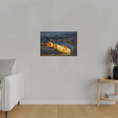Small framed photo of a yellow glass bottle lying on a wet beach, hung on a light gray wall.