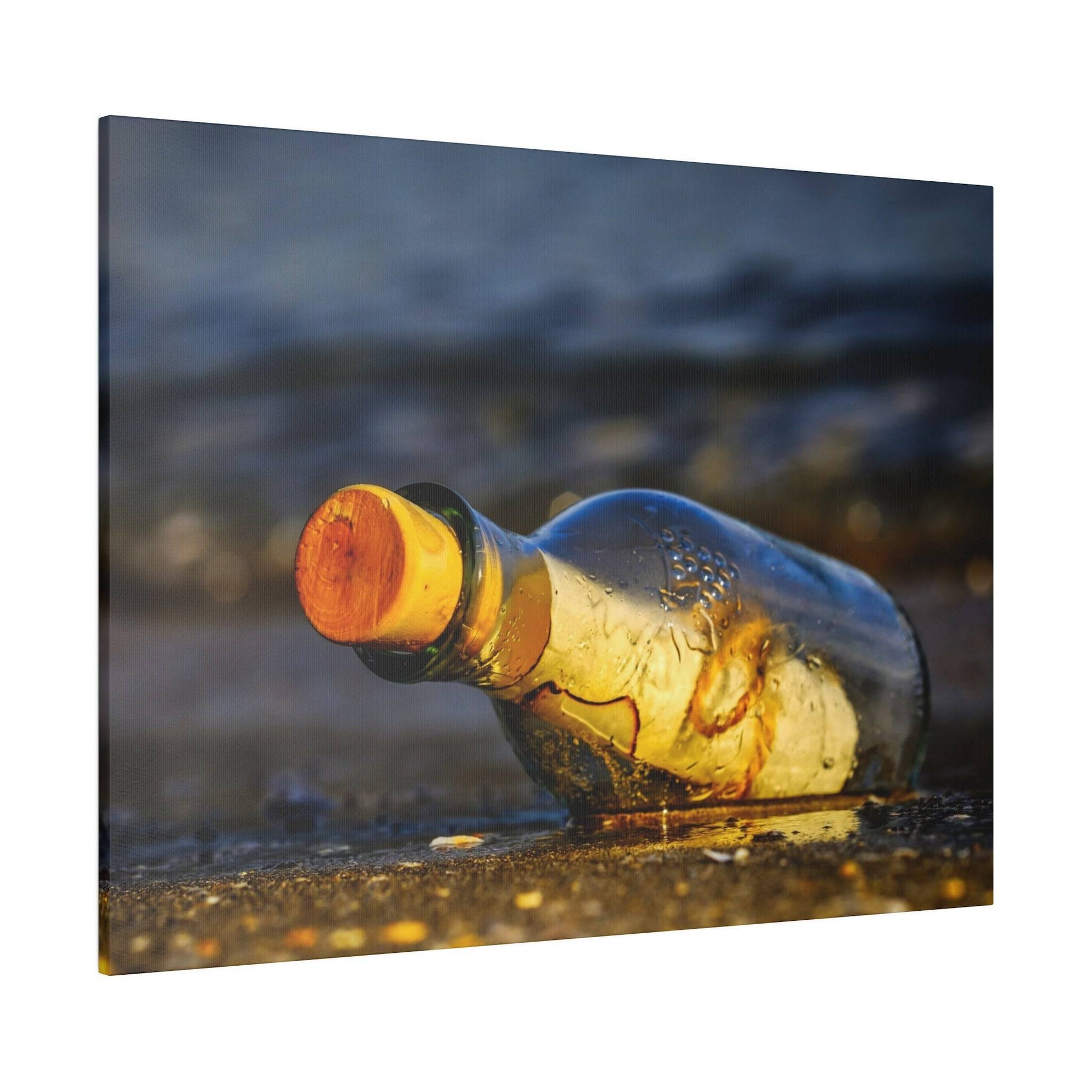 A clear glass bottle with an orange cork lies on wet sand by the sea.