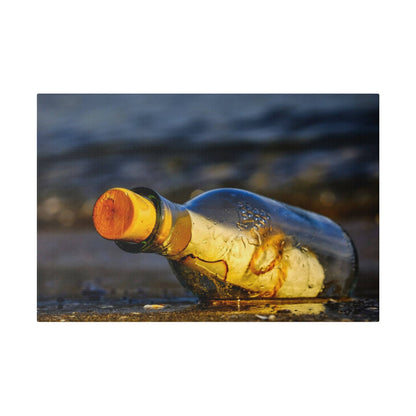 A transparent glass bottle with an orange cap rests on damp sand by the shoreline.