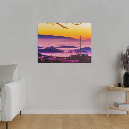 Colorful landscape photo of a sunset over purple fog and rolling hills, hung on a pale gray wall in a living room.