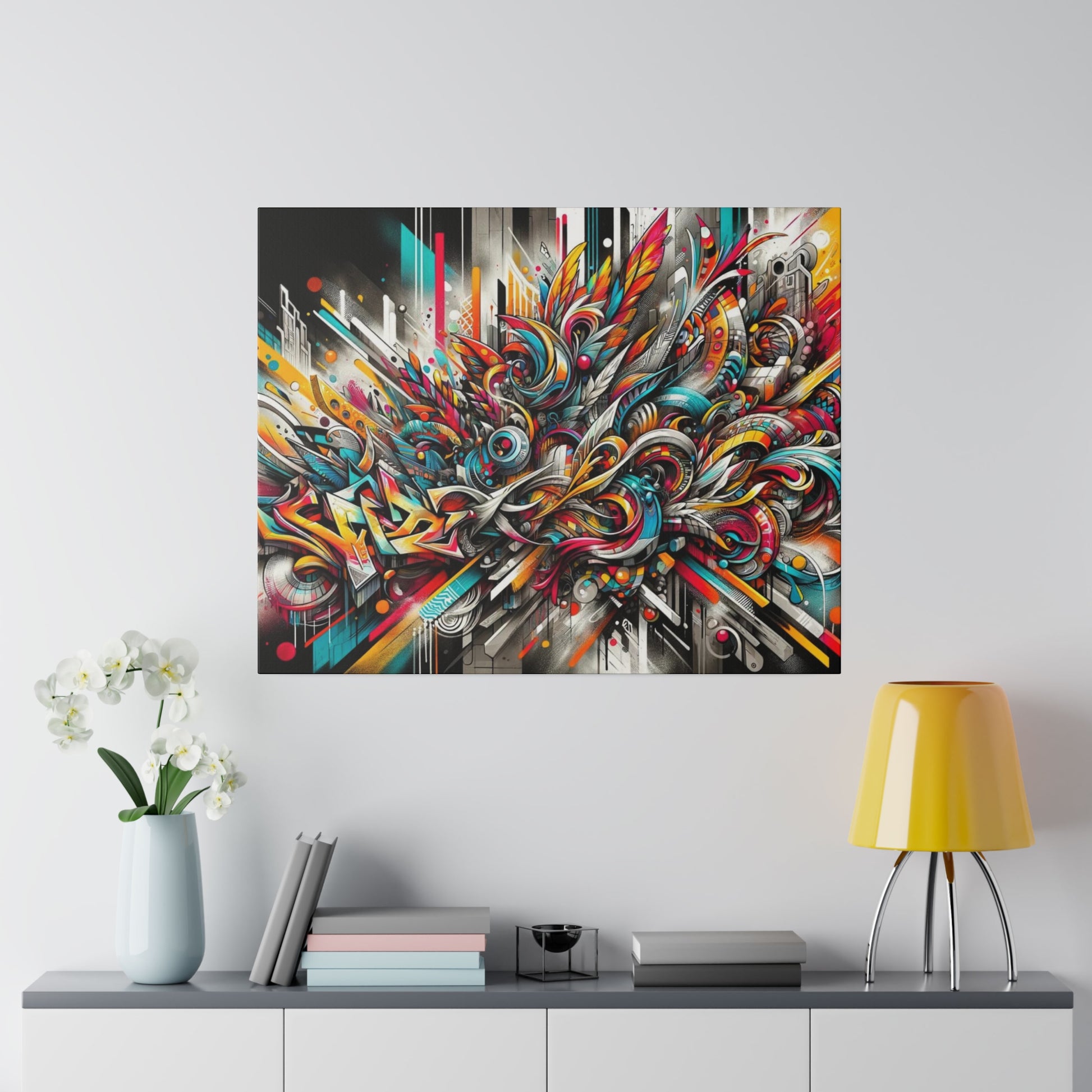 Colorful abstract graffiti painting with swirling, angular shapes hung on a light gray wall above a console with books, a vase, and a
