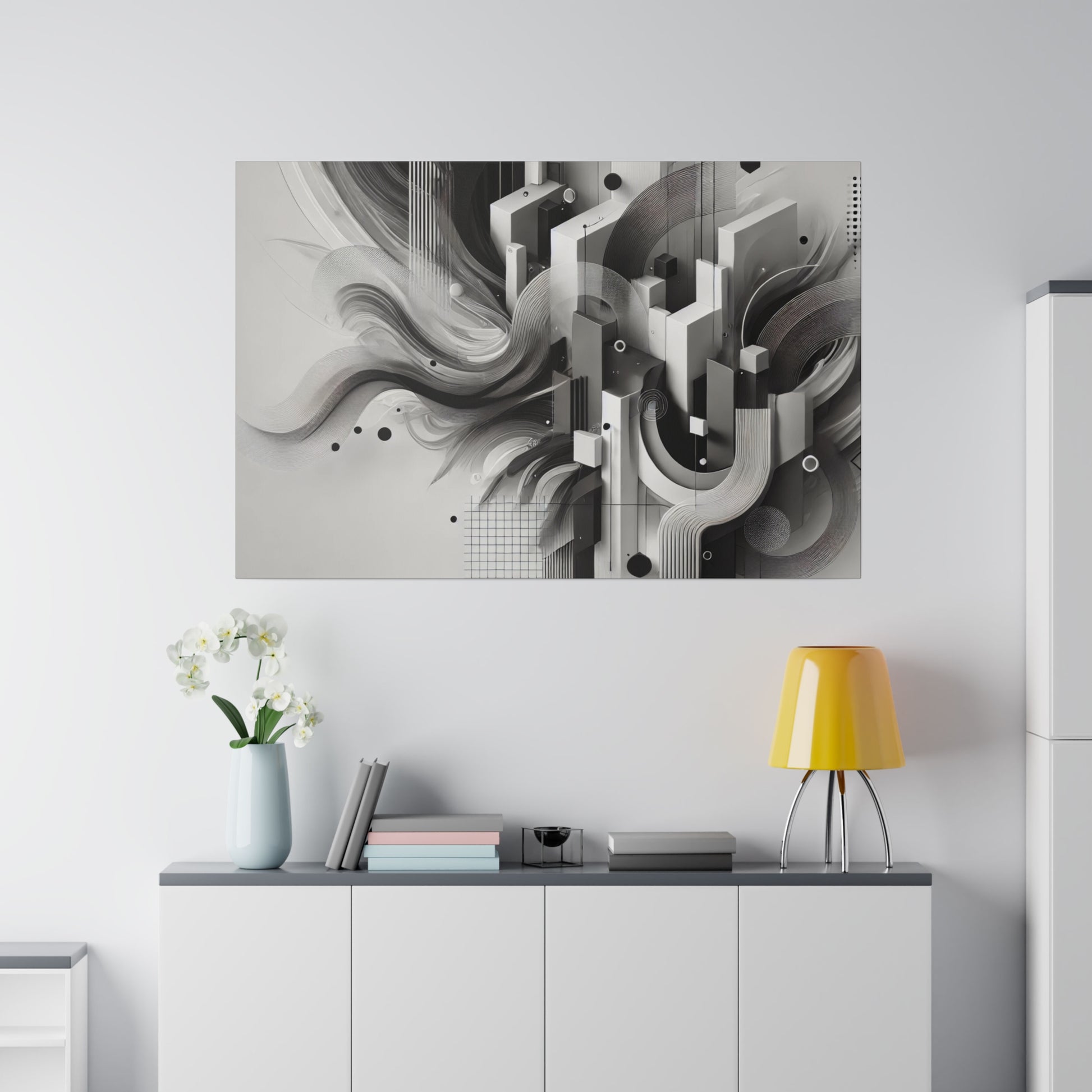 Abstract black-and-white geometric artwork mounted above a white cabinet, with a light blue vase of white flowers and a yellow table lamp