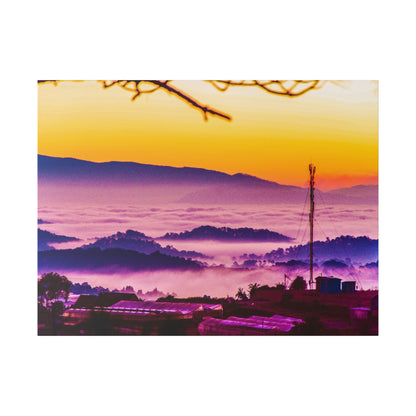 Sunrise over a misty valley with purple fog, silhouetted hills, and a tall utility pole near buildings.