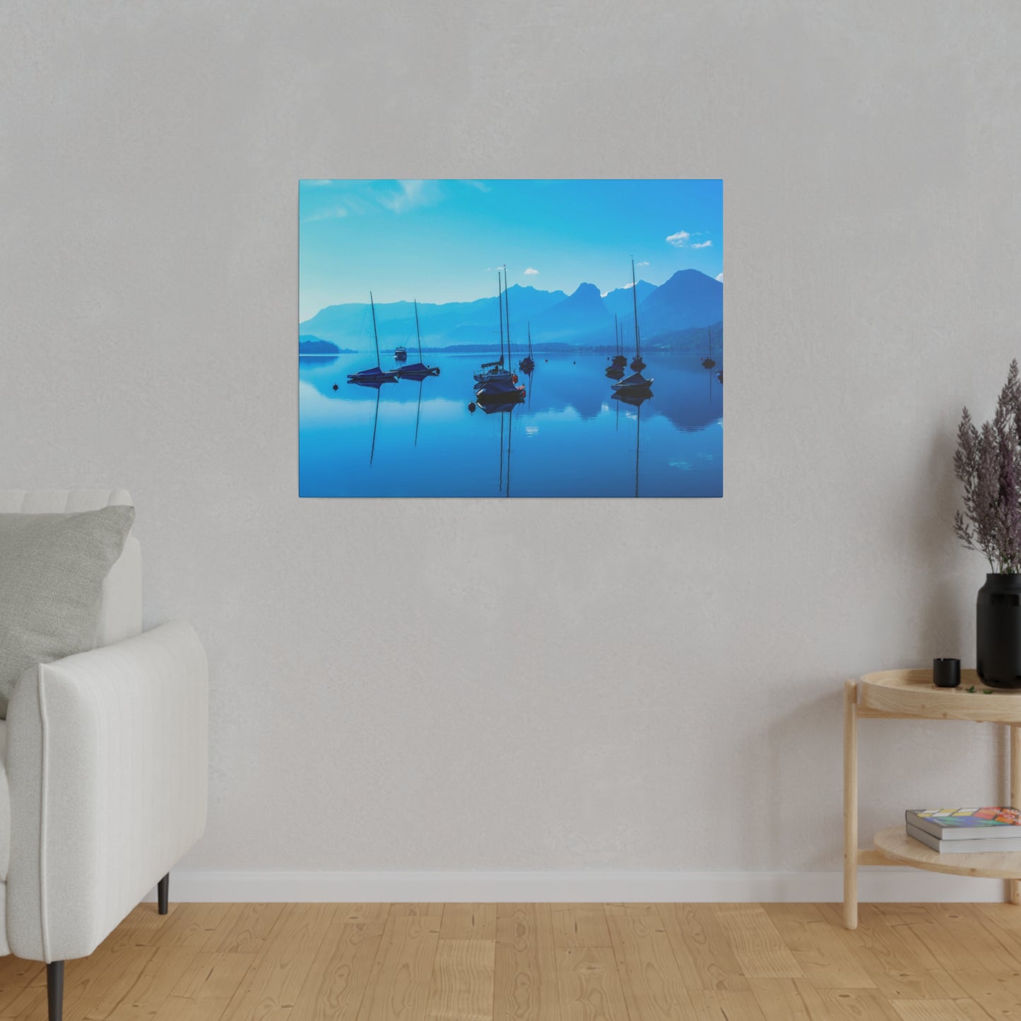 A morning view of a mountain lake with sailboats anchored in the calm water. The blue hues and clear sky create a tranquil and serene atmosphere.