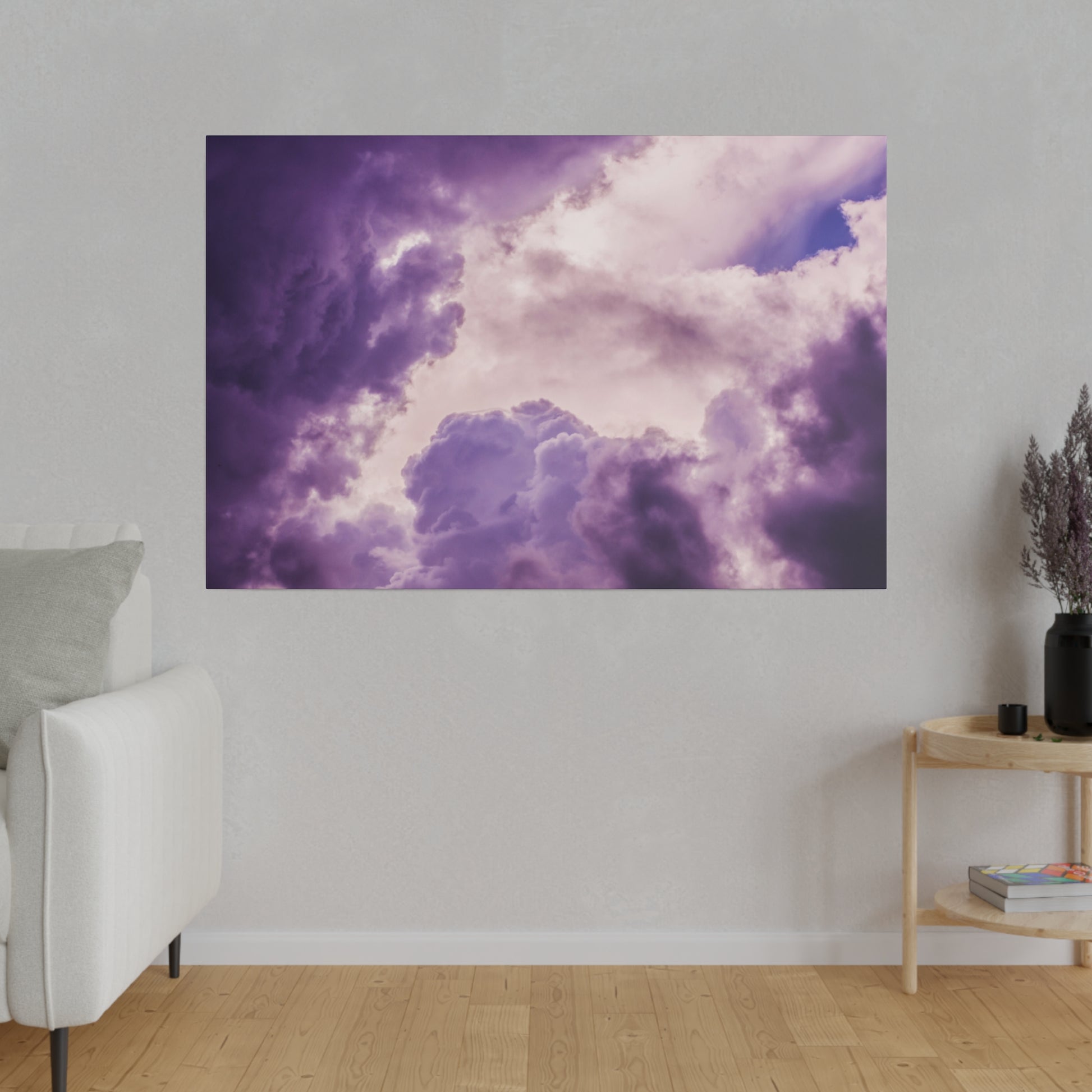 Rectangular wall art print of purple and lavender storm clouds against a pale sky, hung on a light gray living room wall.