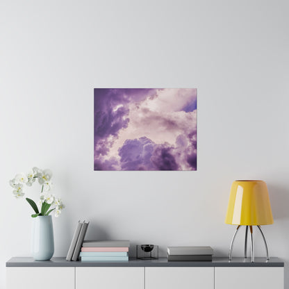 Square wall art depicting a purple and pink cloudy sky hangs above a gray console with a blue vase of white orchids, stacked books, and a