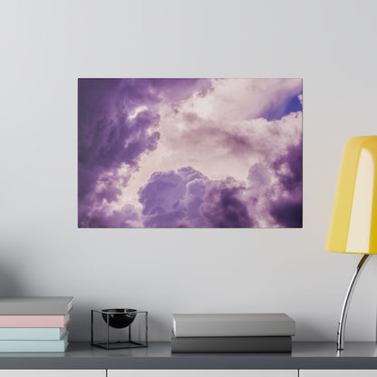 Rectangular wall art depicting purple and pink clouds hangs above a desk with stacked pastel books and a yellow lamp.