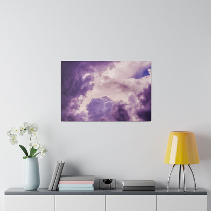 Framed purple cloudscape artwork hangs on a light wall above a sideboard with a pale blue vase, books, and a yellow lamp.