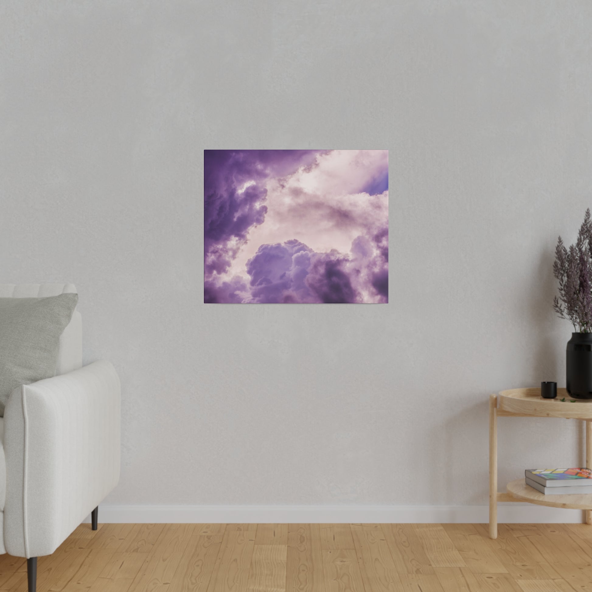 Square art print depicting purple and pink cloudscape hanging on a light gray wall above a wooden floor.