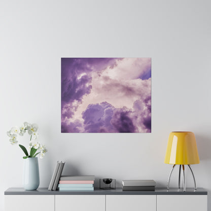 Purple-toned cloud artwork mounted on a light wall above a console with a pale blue vase of white orchids, stacked books, and a yellow