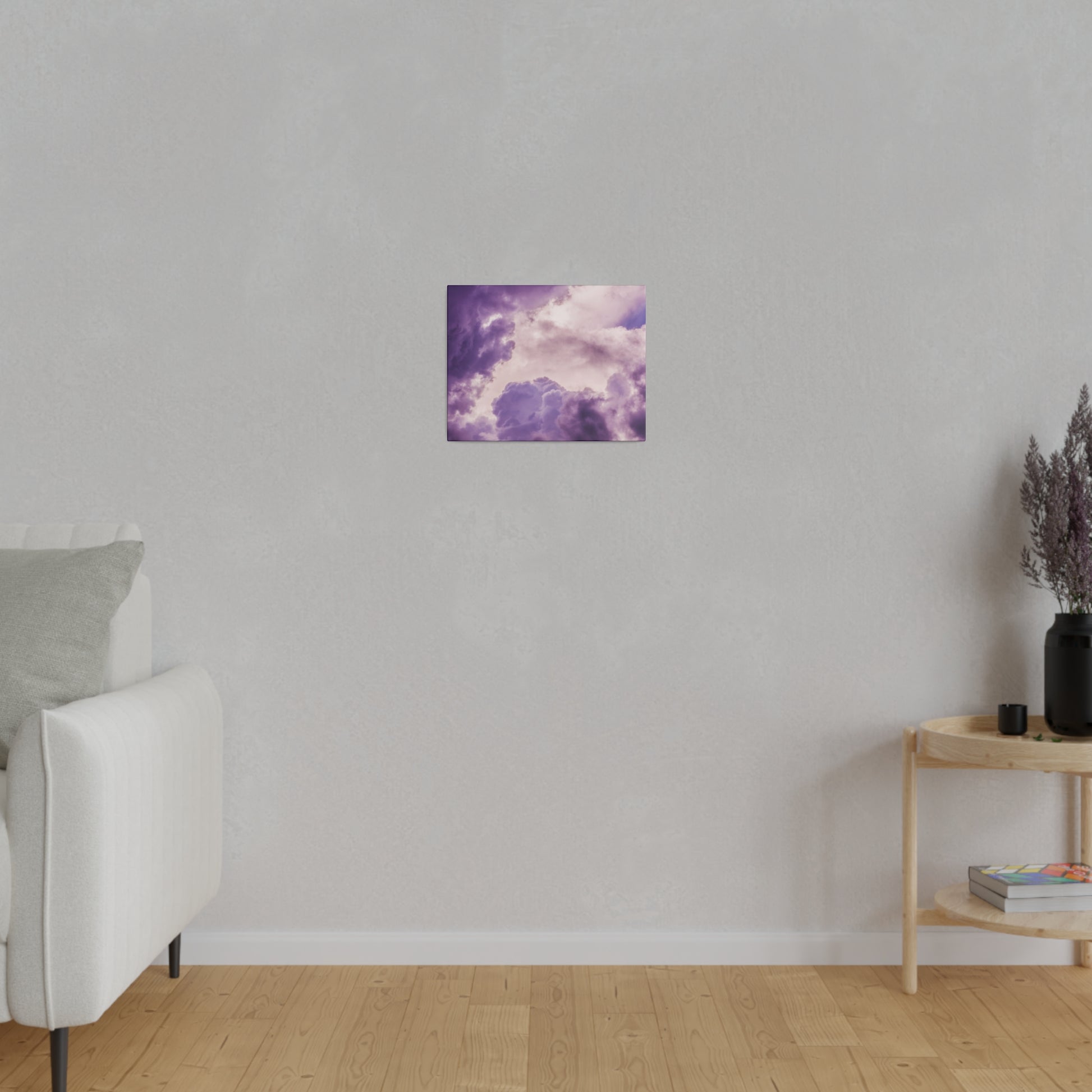 Small square canvas showing purple clouds against a lighter sky, mounted on a light gray wall in a living room.