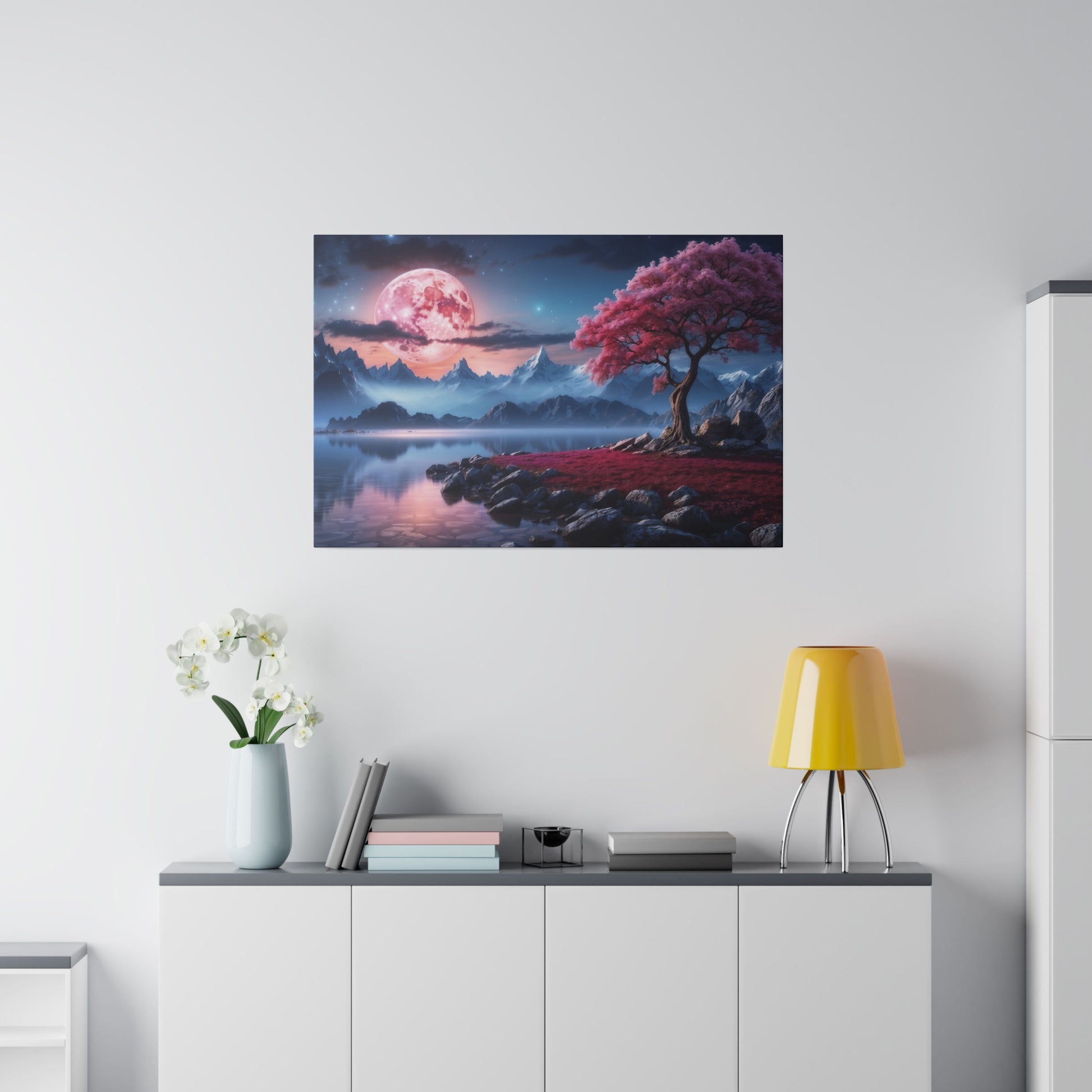 Framed landscape print featuring a pink moon over blue mountains, with a pink-blossomed tree by a reflective lake.