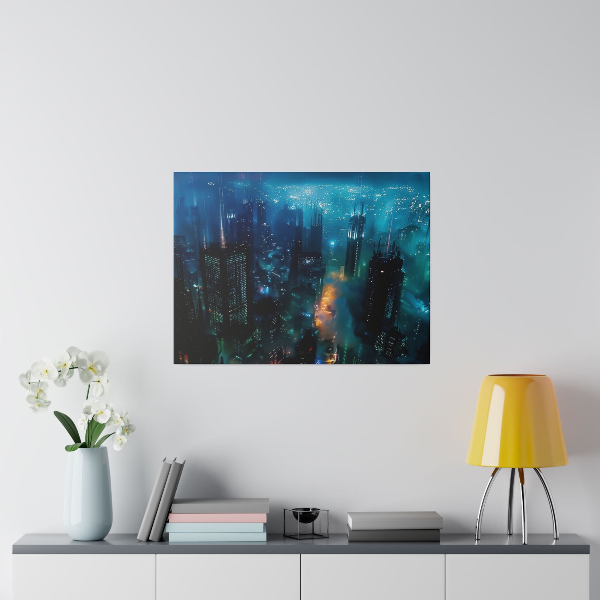 Blue-toned cityscape wall art mounted above a console table with a pale vase of white orchids, books, and a yellow lamp.